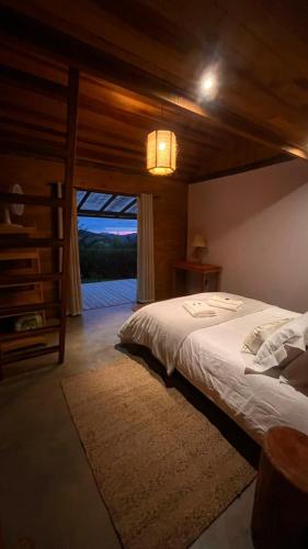 a bedroom with a large bed and a large window at Cabana do Sol -São Francisco Xavier in São José dos Campos