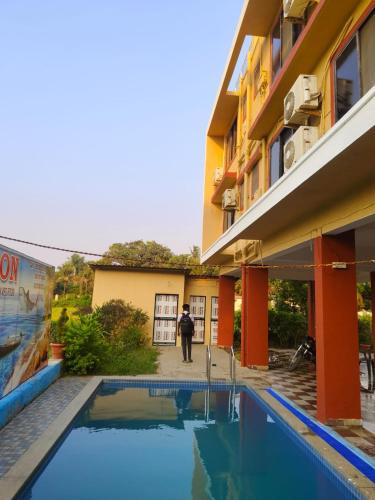 a man standing in front of a building with a pool at Horizon cottage in Nagaon