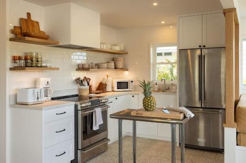 a kitchen with a stainless steel refrigerator and a table at Cottage Three - Hidden Gem on Hanalei River in Hanalei