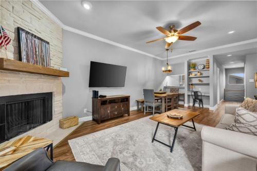 a living room with a fireplace and a ceiling fan at Comal Rive Pool Gruene Hall by Barclé in New Braunfels