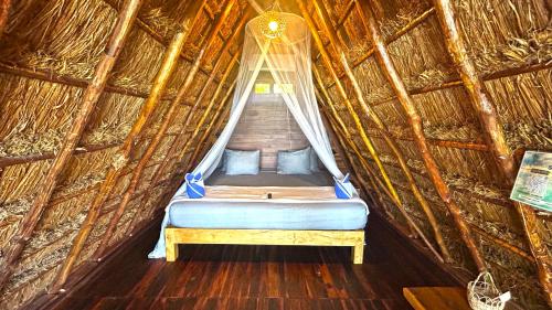 a bed in a straw hut with a window at Paradise Beach Bacalar A Pie De Laguna in Bacalar