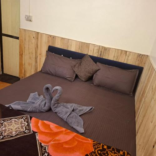 two towel swans sitting on a bed with pillows at ADROSE COTTAGESs in Colva