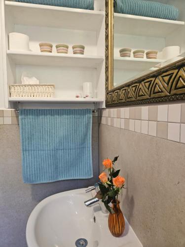 a bathroom sink with a vase with orange flowers on it at Marine View in Plettenberg Bay