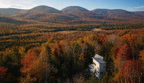 a house in the middle of a forest with mountains at Modern Glass House with Firepit, Views & Private Retreat in Elka Park