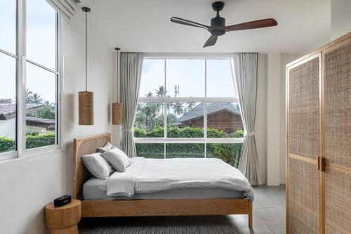 a bedroom with a bed and a large window at Blue Garden Villa A in Ban Madua Wan