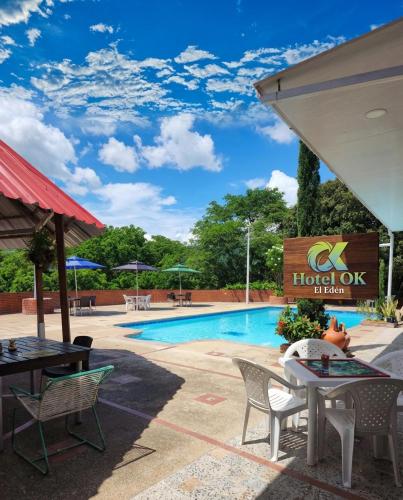 a resort pool with tables and chairs and a hotel ok sign at Hotel OK El Edén in Tocaima