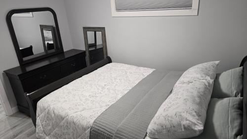 ein Schlafzimmer mit einem Bett und einer Kommode mit Spiegel in der Unterkunft Koko Suites in Regina