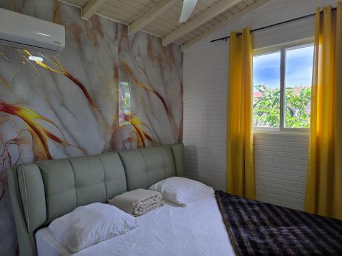 a bedroom with a bed with a painting on the wall at Villa Chelsy in Capesterre-Belle-Eau