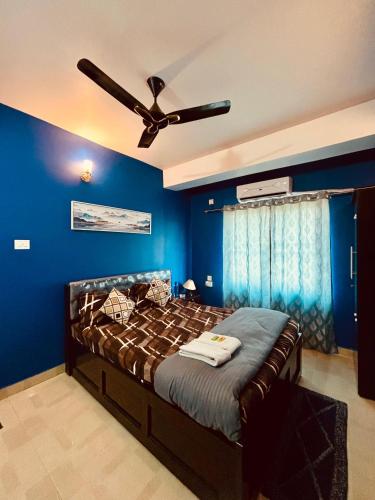 a blue bedroom with a bed with a ceiling fan at Serene Cove Homestay in Dispur