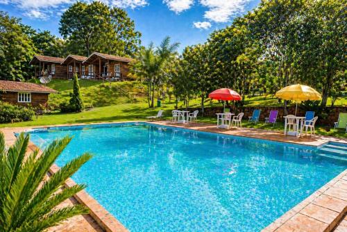 a swimming pool with chairs and umbrellas next to a house at Sopro do Vento Roots Hotel in Analândia