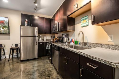 a kitchen with wooden cabinets and a stainless steel refrigerator at The West End Flats Hotel in Roanoke