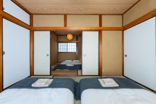 two twin beds in a room with a mirror at Coto House Kamakura RoomB in Kamakura