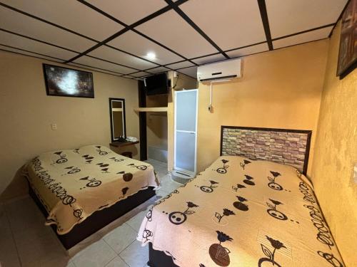 a small room with a bed and a refrigerator at Hotel Luxi in Playa Azul