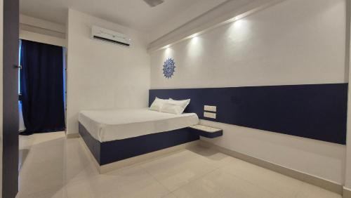 a small bedroom with a bed and a blue and white wall at BLEU by NIRVANA in Mahabalipuram