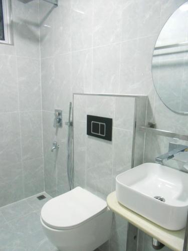 a bathroom with a toilet and a sink and a mirror at Bougainvillea Breeze in Male City