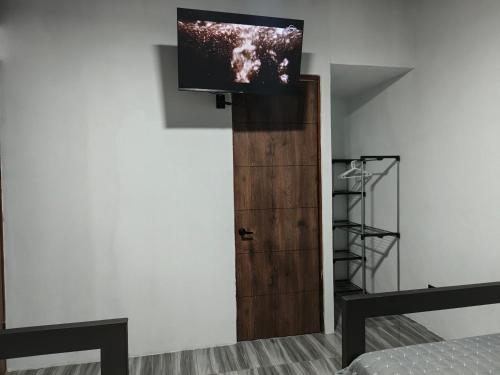 ein Zimmer mit einem Fernseher an der Wand und einer Tür in der Unterkunft Hotel Dinopark in Salado