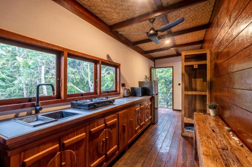 a kitchen with wooden cabinets and a sink and windows at Hidden Paradise West Sumbawa Yo Yos in Sekongkang Bawa