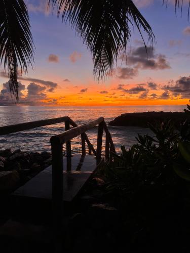 a sunset over the ocean with a wooden bridge at Sunset Cove Villa in Grand'Anse Praslin