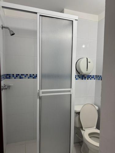 a bathroom with a toilet and a glass shower door at Hotel Cielo de Tambores in Cali