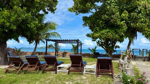a group of chairs and a picnic table on the beach at Sunset Cove Villa in Grand'Anse Praslin