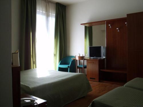 Habitación de hotel con 2 camas y TV en Hotel Traghetto, en Civitavecchia
