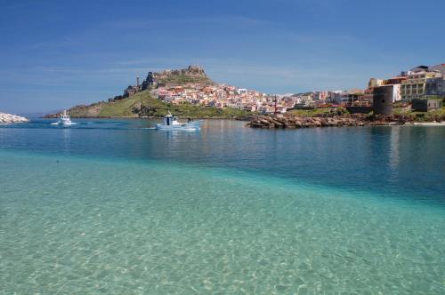 a small boat in a body of water with a city at B&B Colti Di Rosa in Castelsardo