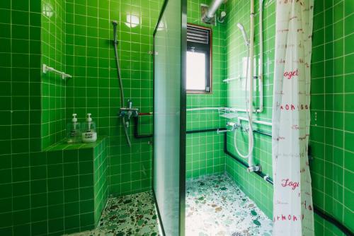 a green tiled bathroom with a shower and a sink at Yasuragi Nakasu in Fukuoka