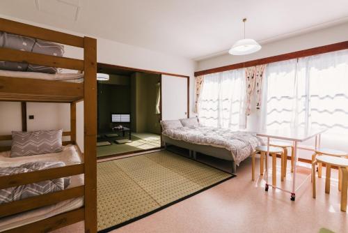 a bedroom with bunk beds and a table and a dining room at Yasuragi Nakasu in Fukuoka