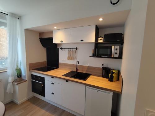 a kitchen with white cabinets and a wooden counter top at Appartement Centre in Lourdes
