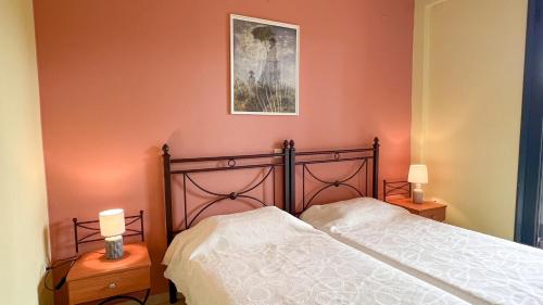 a bedroom with a bed and two tables with lamps at Ionian Bay Studios in Lefkada