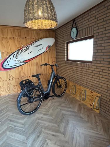 a bike parked in a room with a surfboard on the wall at Beachhouse Anna, 1 minute walk to the beach and centre of Katwijk, Free private parking next to the house ! in Katwijk aan Zee