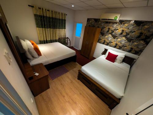 a small room with two beds and a wall at Diva Villa Airport Transit Hotel in Katunayaka