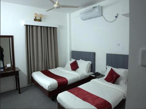 a hotel room with two beds and a mirror at Al Aziz Hotel Sylhet in Sylhet