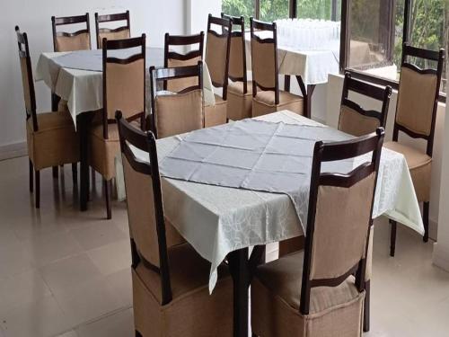 a dining room with tables and chairs with white table cloth at Al Aziz Hotel Sylhet in Sylhet