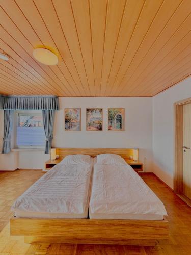 a large bed in a room with a wooden ceiling at Pension Dang in Norddeich