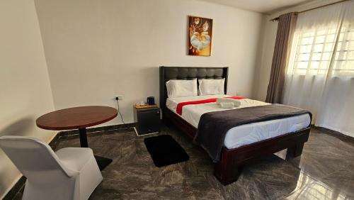 a bedroom with a bed and a table and a chair at Malbon Green Executive Plus Lodge in Kafue