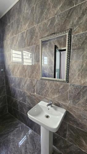 a bathroom with a sink and a mirror at Malbon Green Executive Plus Lodge in Kafue