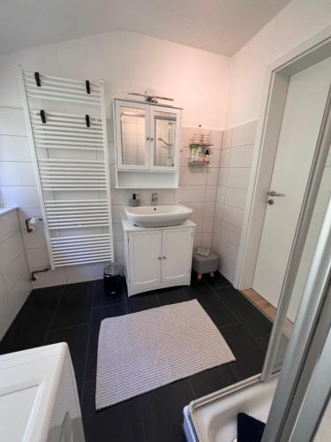 a white bathroom with a sink and a mirror at Anna's Waldchalet - FeWo Waldblick in Hannoversch Münden