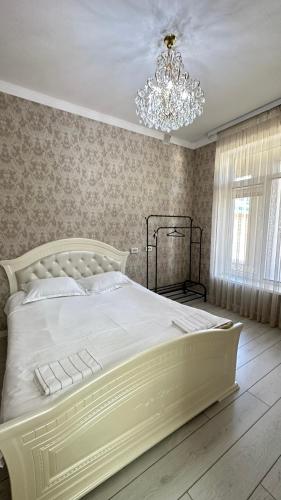 a bedroom with a large white bed with a chandelier at Гостевой дом in Tokmok