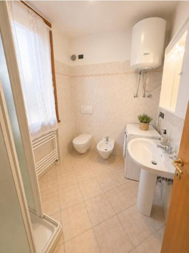 a white bathroom with a toilet and a sink at Villa Dascia - Agenzia Cocal in Caorle