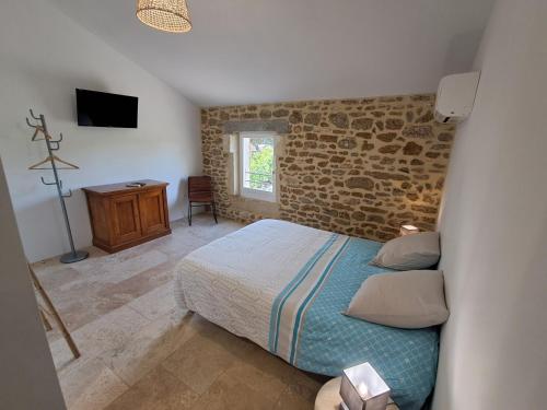 a bedroom with a bed and a stone wall at Chez Véro Gîte & Chambres d'hôtes " Le Juvaquatre " in Suze-la-Rousse