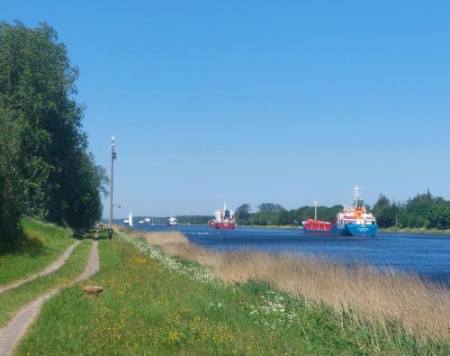 three boats are docked on a river at Kanalkajüte Wilhelm in Hanerau-Hademarschen
