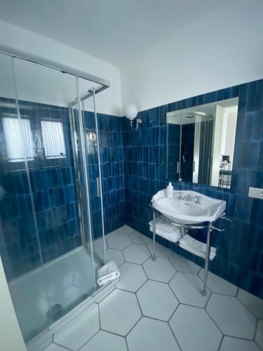 a blue tiled bathroom with a sink and a shower at Casa Stinga in Capri
