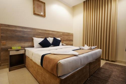 a bedroom with a large bed with a wooden headboard at فندق النخبة الماسي - Diamond Elite Hotel in Medina
