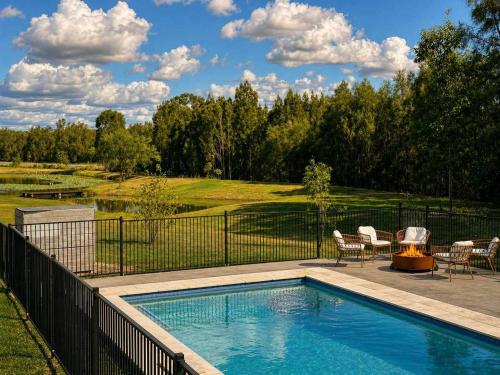 a swimming pool with chairs and a golf course at Chardonnay Escape in Pokolbin