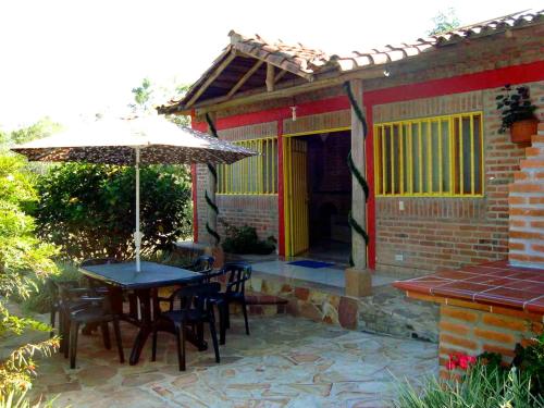 a patio with a table and chairs and an umbrella at Cabañas La Carolina - Mesa de Los Santos in Los Santos