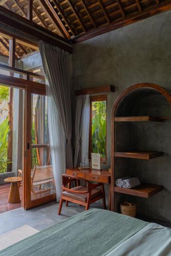 a bedroom with a desk and a bed and a desk and a window at The Salty Jungle in Cijulang Nusawiru Airport