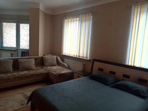 a bedroom with a bed and a couch and windows at Абай2 103 in Astana