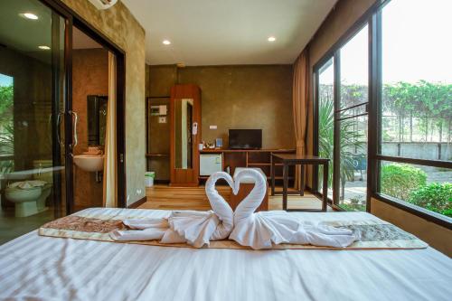 two white swans are sitting on a bed in a room at Blue River Resort in Phitsanulok
