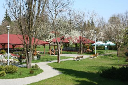 a park with benches and tables and umbrellas at Hotel z Sanatorium Uzdrowiskowym Knieja Spa&Wellness in Supraśl